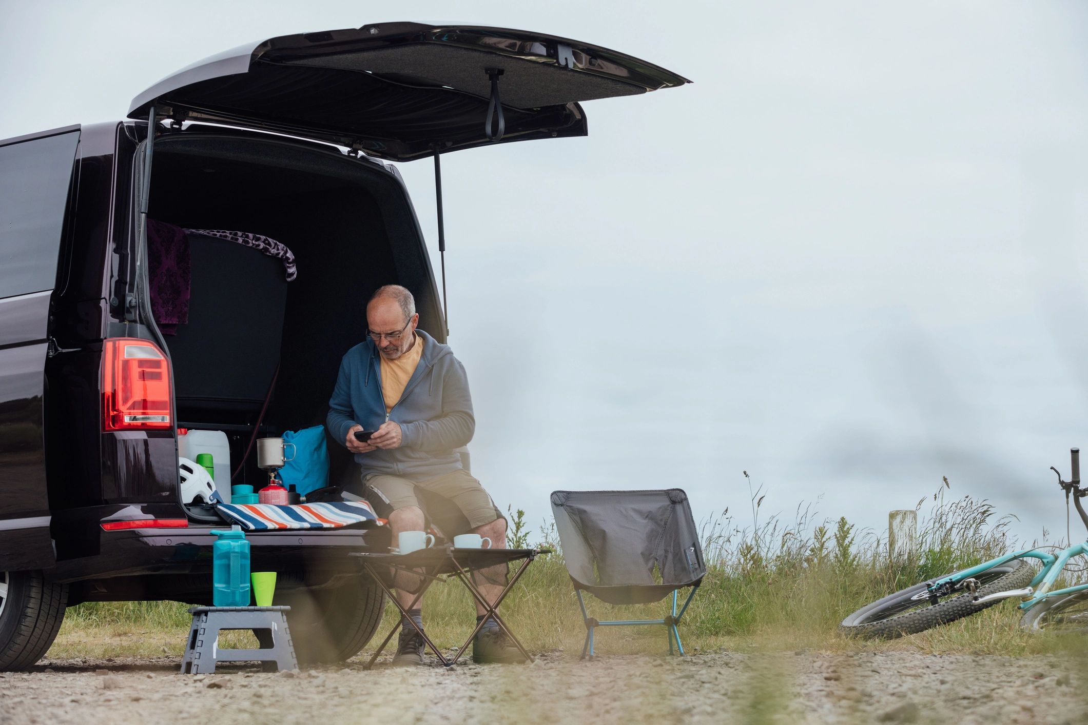 Traveler planning a route beside a camper van on the coast
