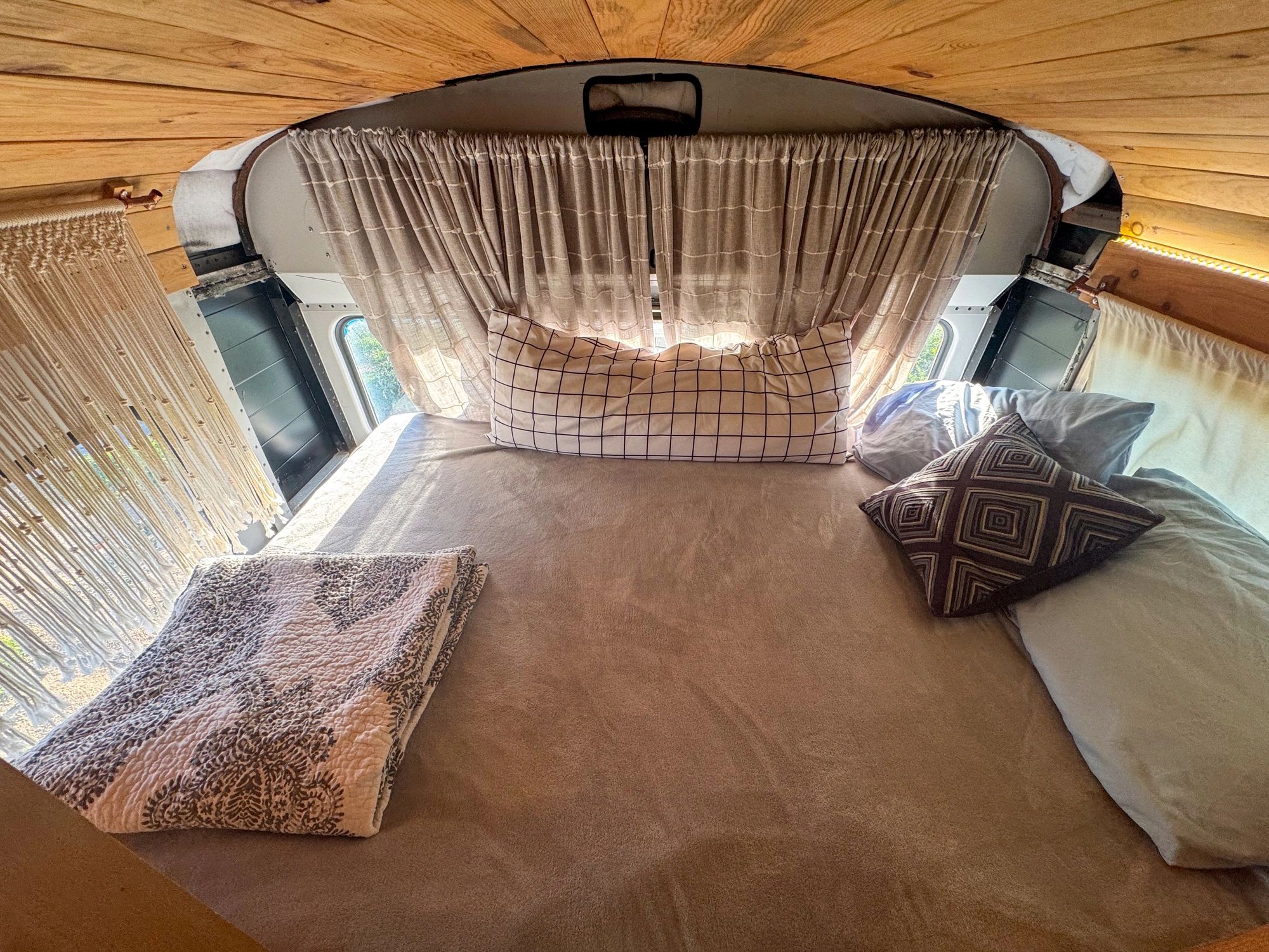 Cozy handcrafted camper sleeping area with custom woodwork